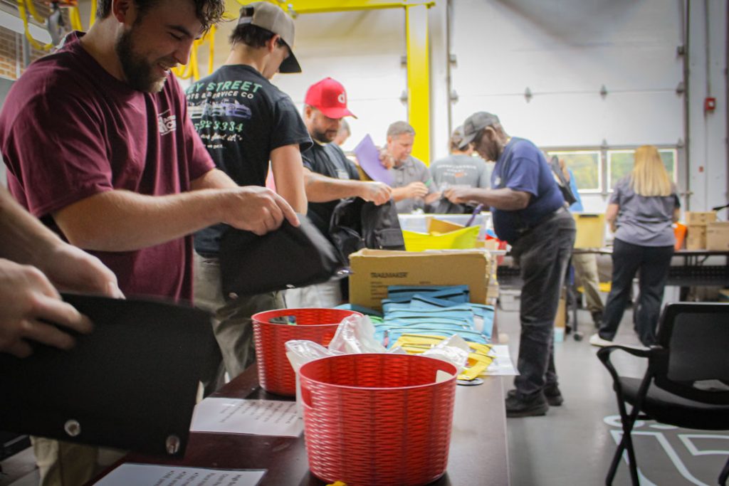ACECO Volunteers forming an assembly line to pack essential school supplies into backpack donations