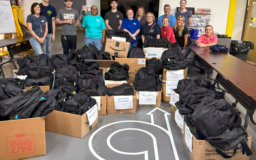 ACECO volunteers gathered around the backpacks filled with essential school supplies for students across Berks County