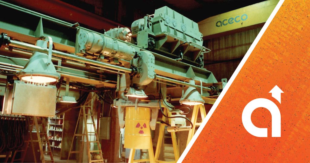 "Industrial machinery and pipework in a warehouse, overlaid with an orange graphic and the ACECO logo